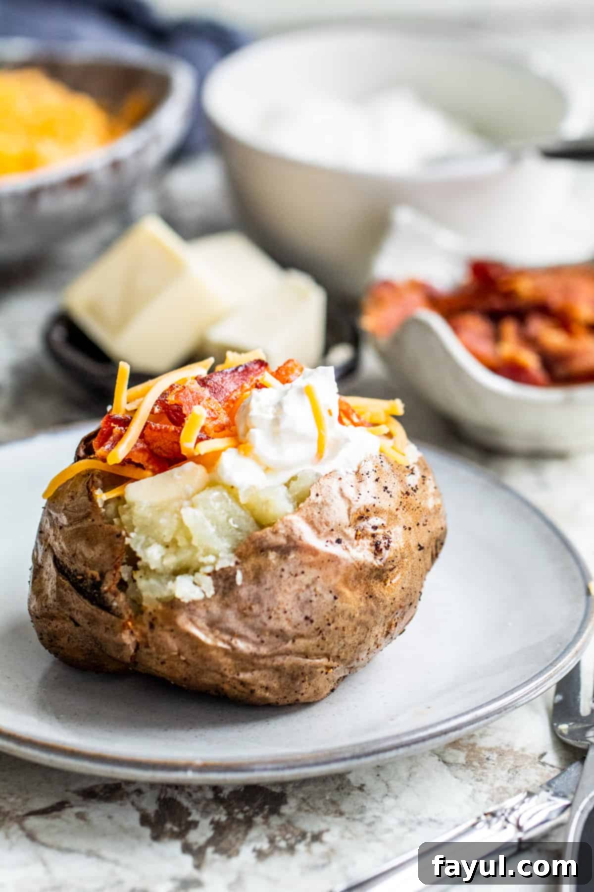 Baked potato on gray plate loaded with toppings.