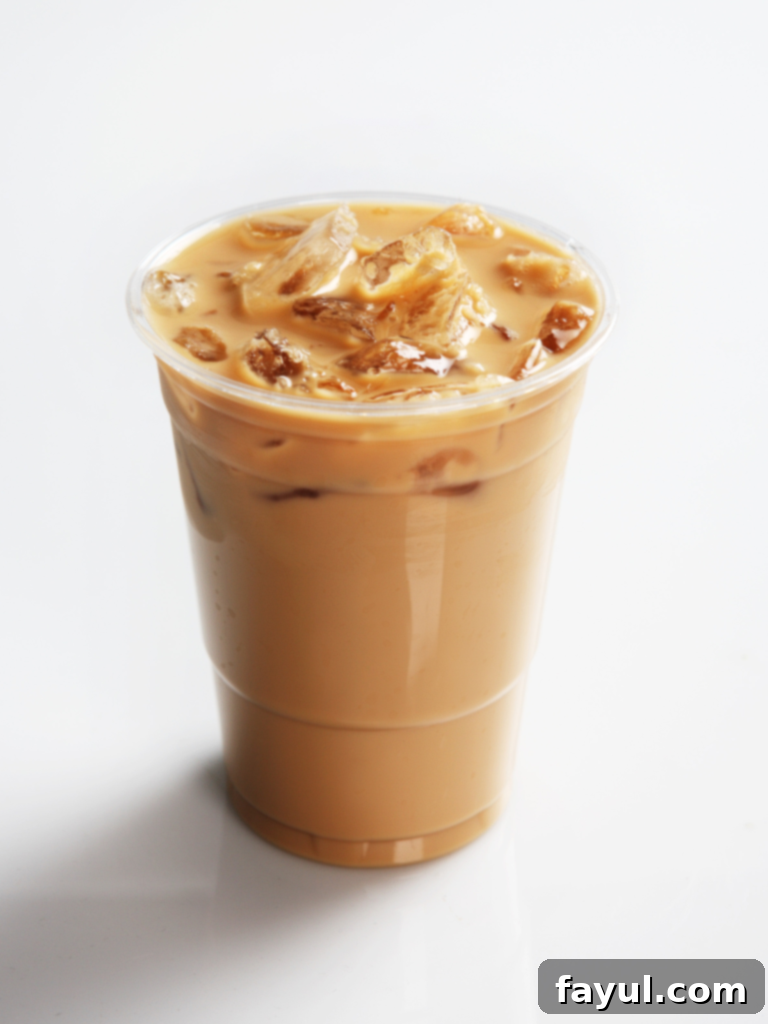 A refreshing Iced Chai Tea Latte in a clear Starbucks cup with whipped cream and cinnamon sprinkles.