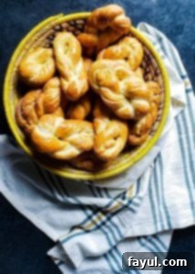 A dozen homemade soft pretzel twists in a yellow and cream woven basket, set on a blue counter with a plaid towel.