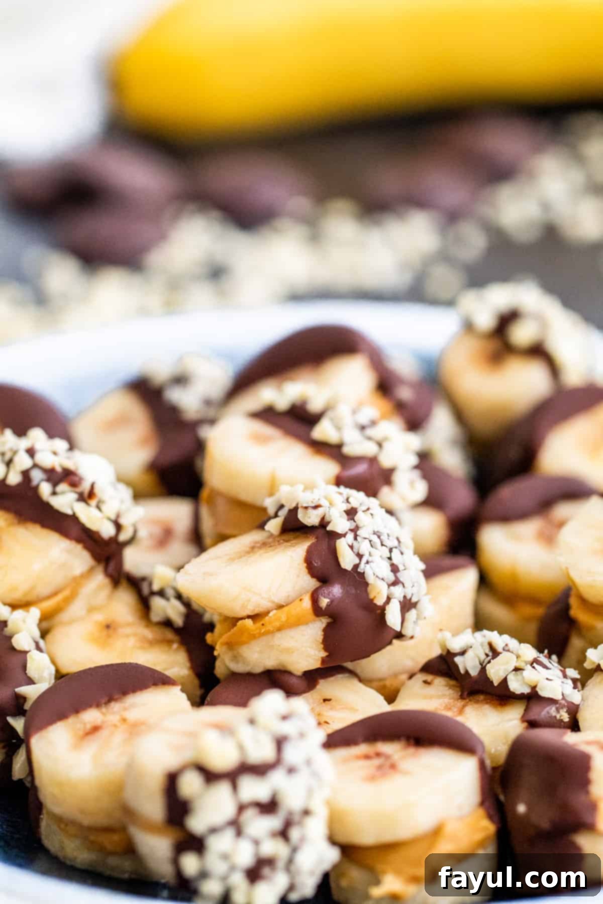 A plate filled with delicious frozen chocolate peanut butter banana bites, showcasing their smooth chocolate coating and a sprinkle of nuts.
