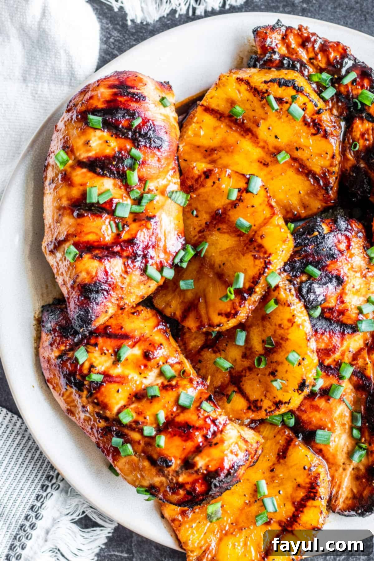 Overhead shot of Hawaiian BBQ chicken with slices of pineapple on white plate, ready to serve.