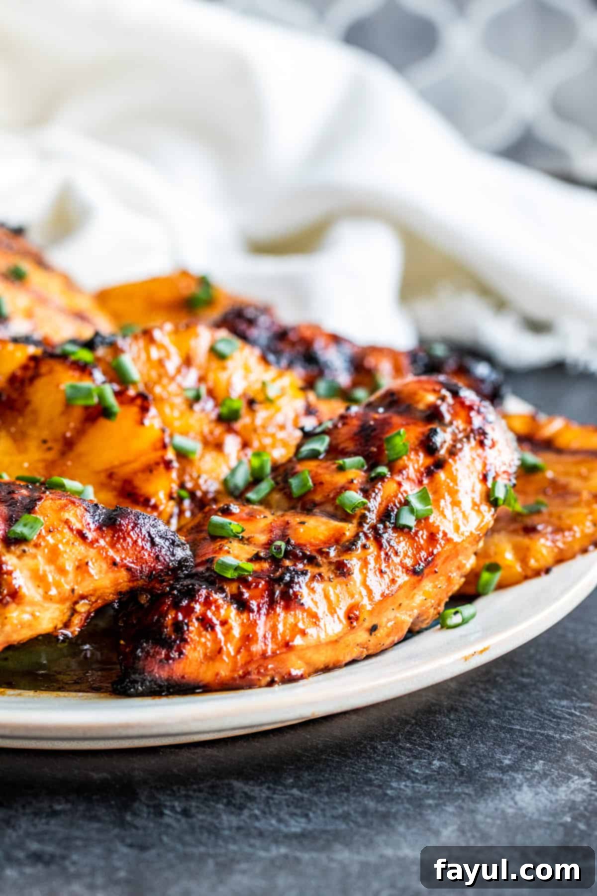 Close-up shot of grilled Hawaiian BBQ chicken and pineapple on a white platter, perfectly cooked.
