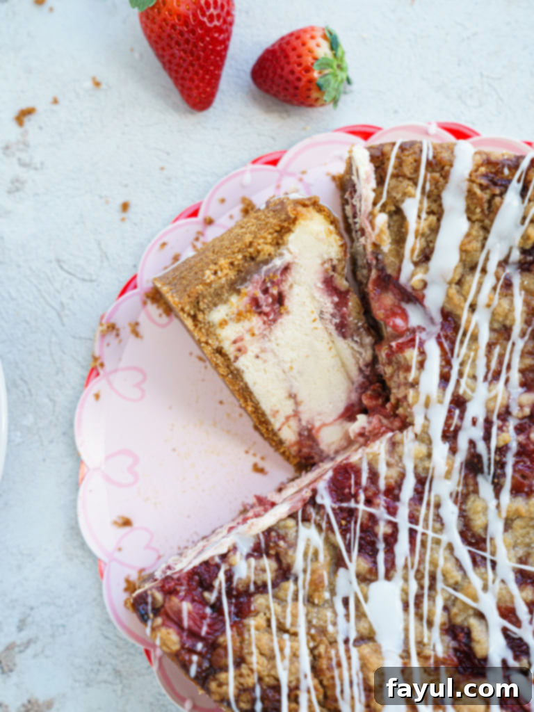 A slice of Roasted Strawberry Crumble Cheesecake with a creamy filling, vibrant strawberry swirls, and a golden-brown crumble topping.