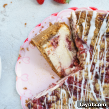 A beautiful whole Roasted Strawberry Crumble Cheesecake with a perfect slice removed.