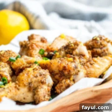 Crispy Air Fryer Lemon Pepper Chicken Wings 7 Wooden bowl filled with lemon pepper wings on white counter.