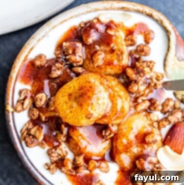 Overhead shot of bananas on top of granola and yogurt in small tan bowl.