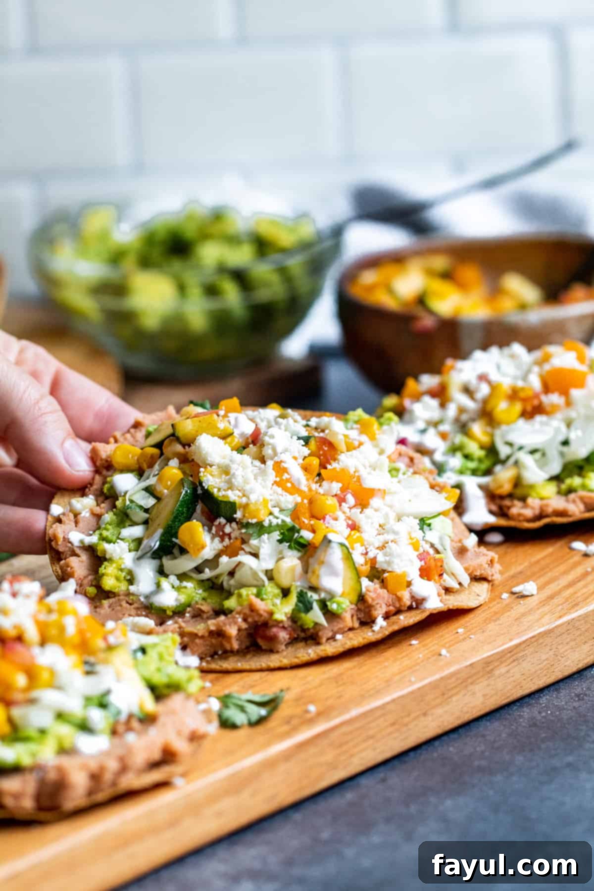 Crispy Vegetarian Tostadas with Bright Cilantro Lime Slaw 9 Hand picking up tostada off of cutting board.
