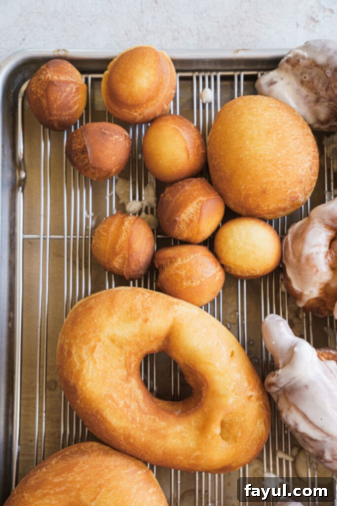 Glazed brioche donuts cooling on a wire rack, with some donut holes