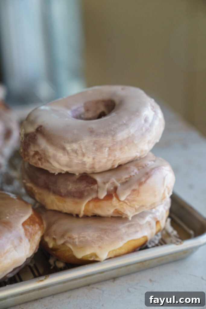 A stack of three brioche donuts with clear vanilla glaze, ready to eat