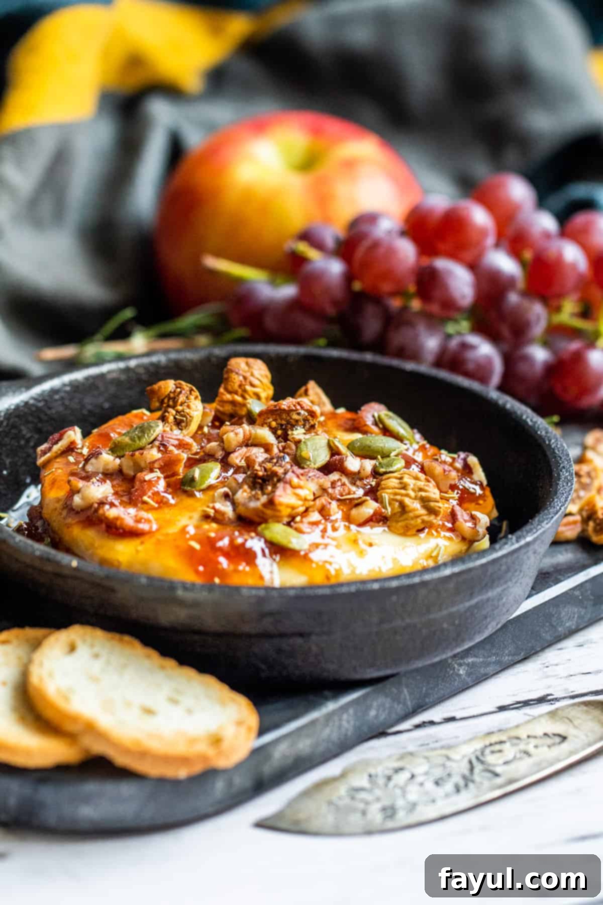 Brie in small cast iron skillet with grapes in the background.