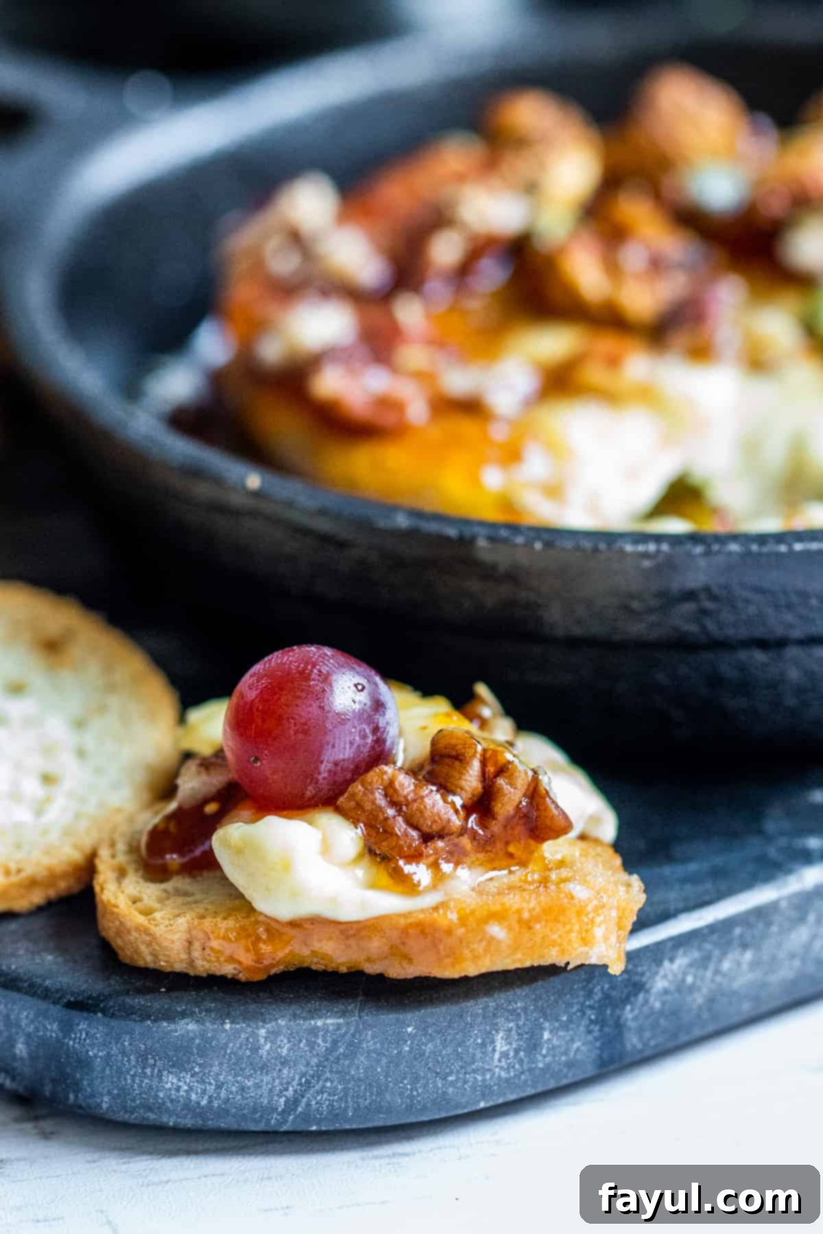 Cheese on bread with grape on top.