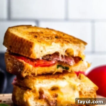 Stack of two bacon grilled cheese sandwiches on wooden cutting board.