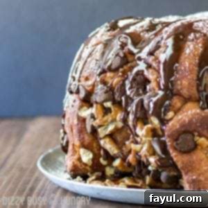 Side shot of whole chocolate pretzel monkey bread on a white plate on a wooden table.