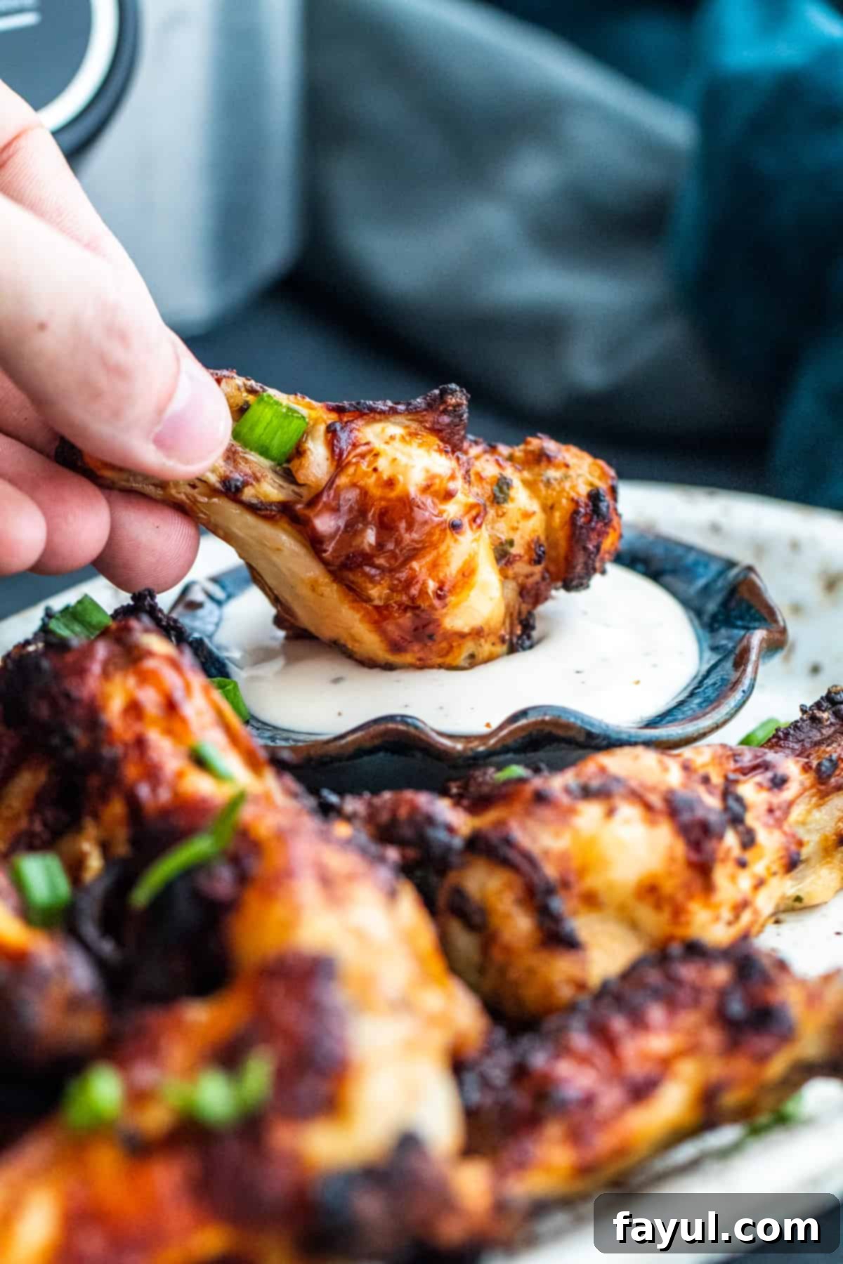 Hand dipping wing into small bowl of ranch.