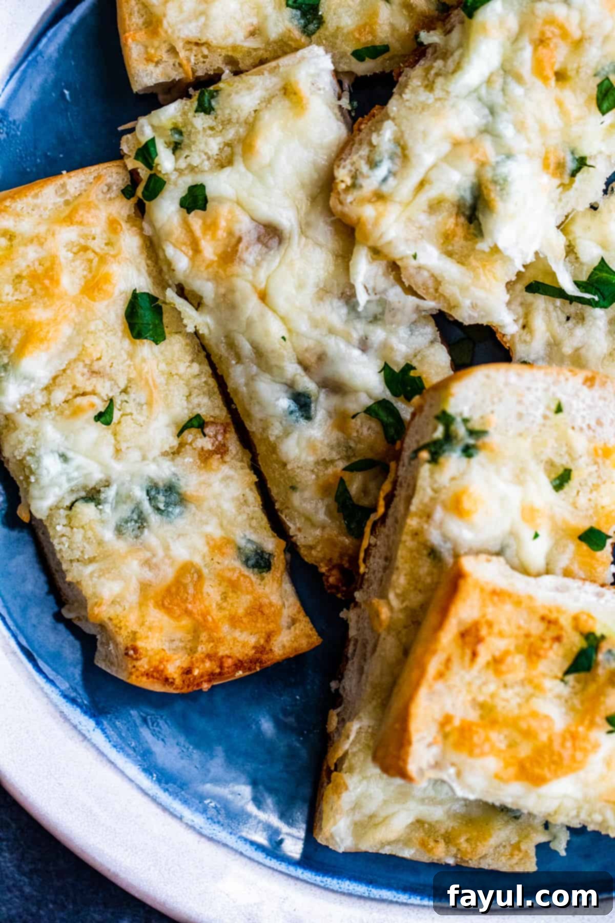 Overhead shot of sliced garlic bread sticks on blue plate, garnished with fresh parsley.