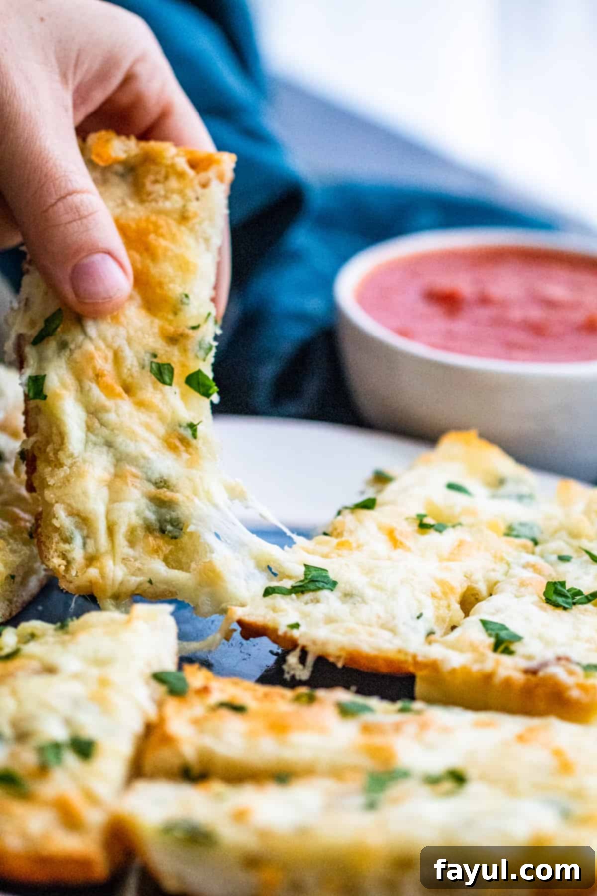 Hand pulling a slice of air-fried cheese garlic bread, showing the cheese pull.