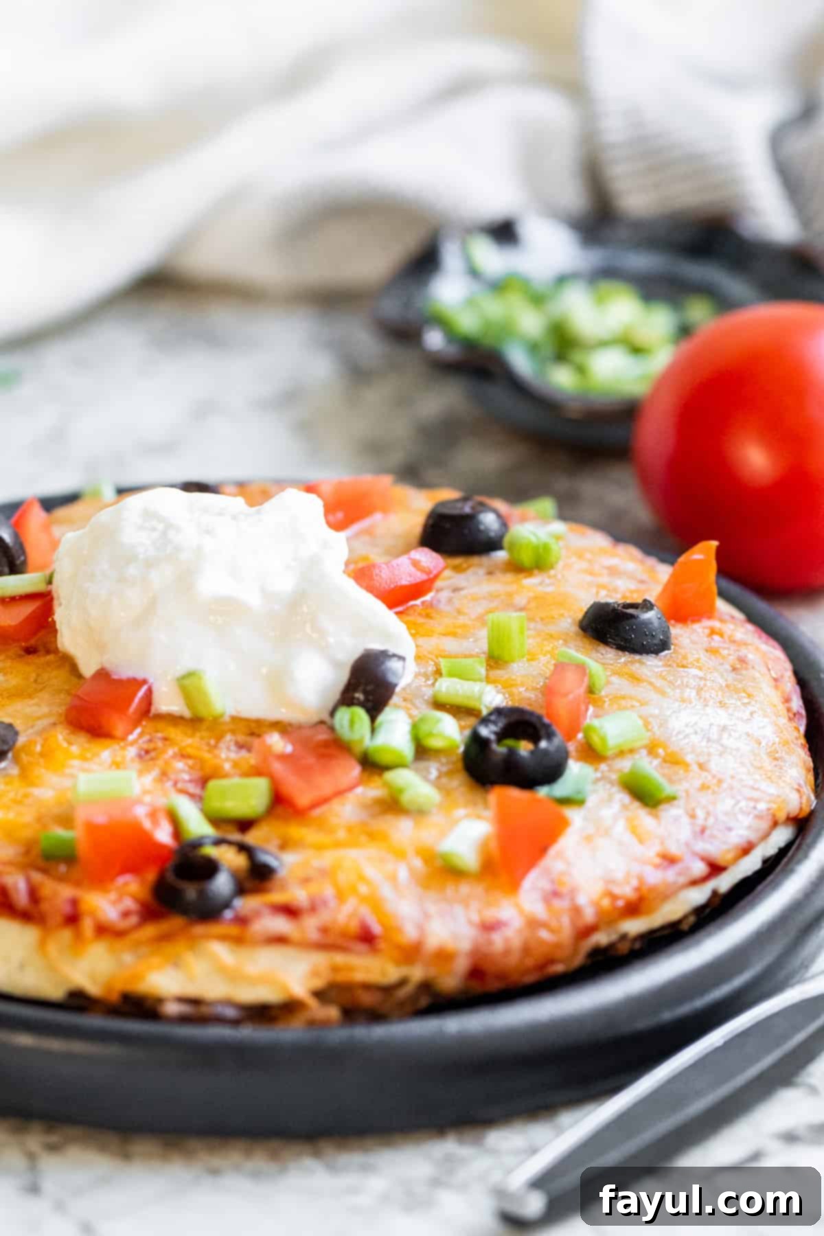 Mexican pizza on a black plate on a white counter.
