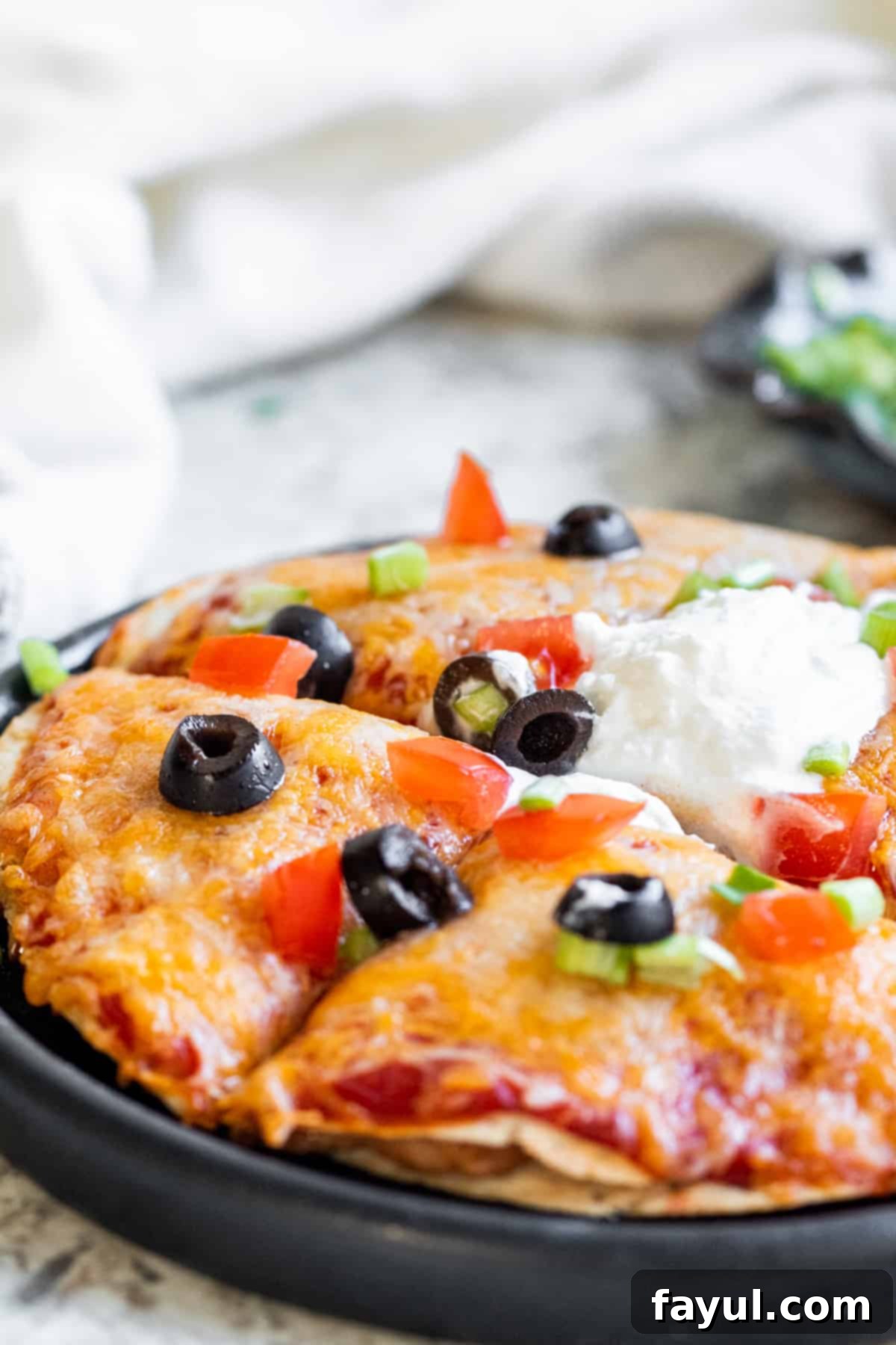 Close up shot of taco pizza sliced on a black plate.