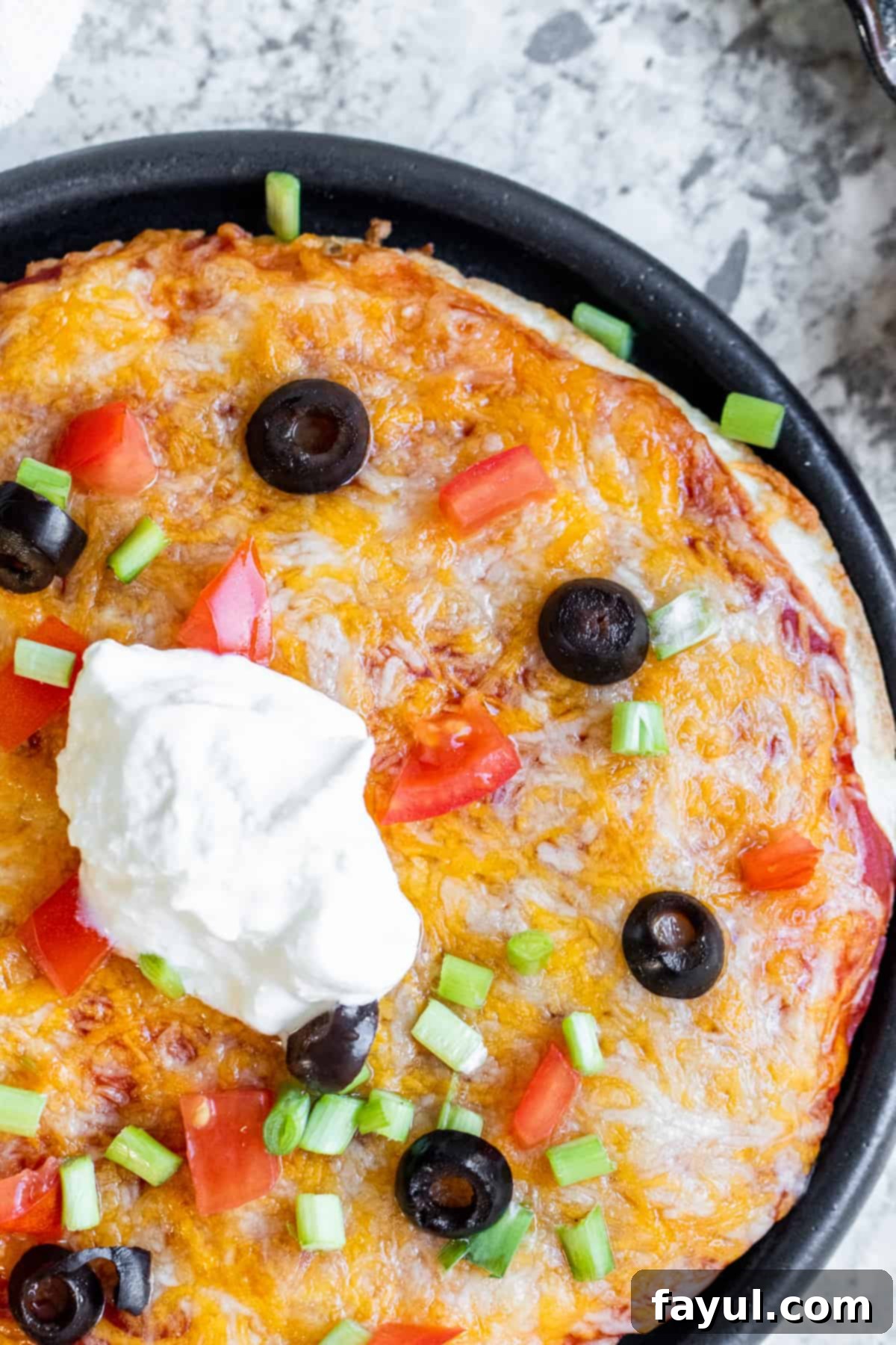 Overhead shot of taco bell Mexican pizza on a black plate.