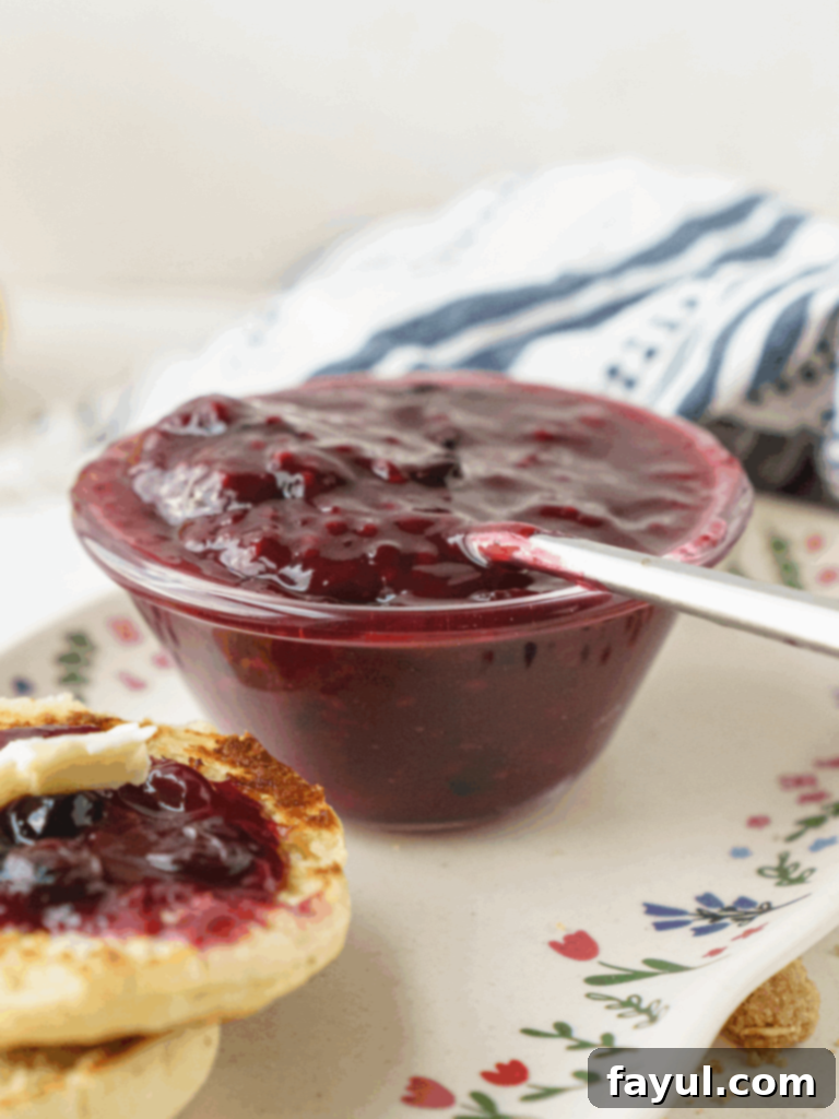 A jar of homemade Triple Berry Jam with fresh berries scattered around