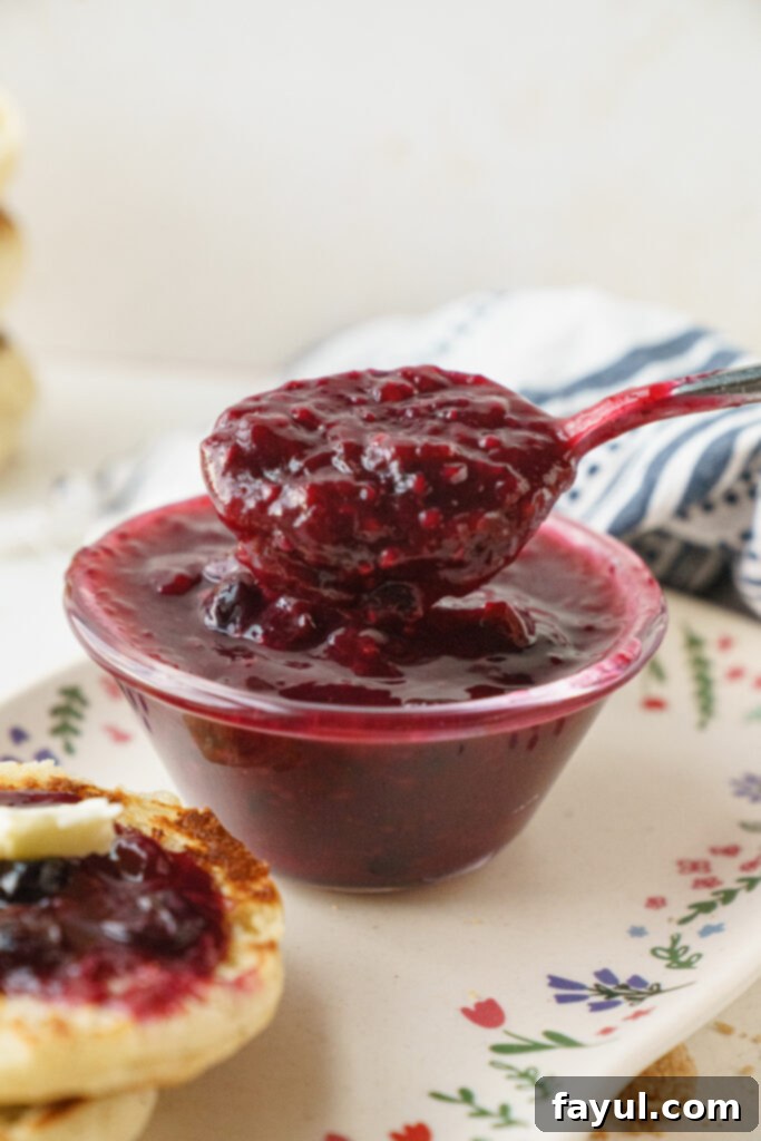 The process of mashing berries in a saucepan for homemade jam