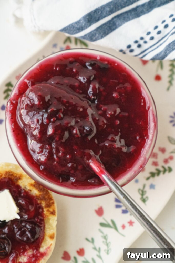 Triple Berry Jam in a jar with a spoon, ready to be enjoyed