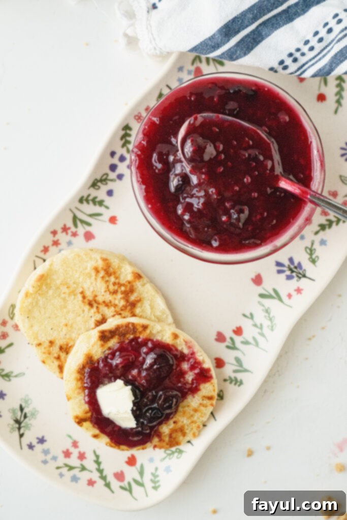 Two jars of homemade Triple Berry Jam, one open with a spoon, highlighting its texture