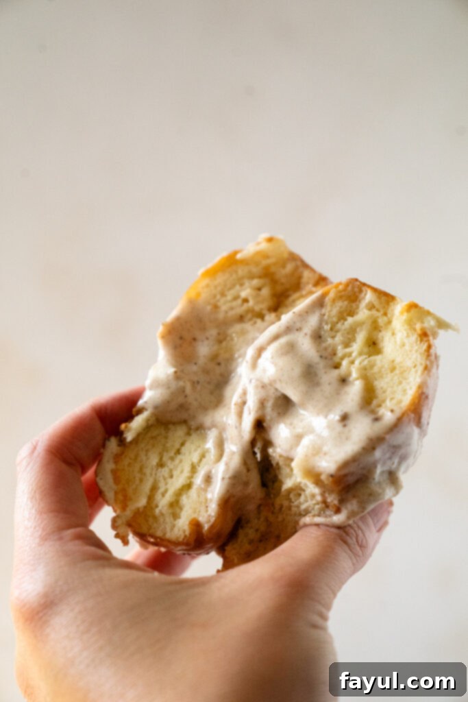 Dipping fluffy chai custard donuts into a bowl of sweet chai glaze, showing the smooth, shiny coating.