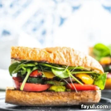 Straight on shot of vegetable sandwich on a dark gray plate with white and blue background.