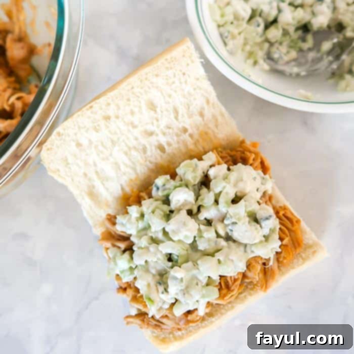 Close up shot of pulled chicken and celery relish on a sandwich roll with a white background.