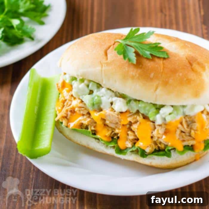 Side view of buffalo chicken sandwich with side of celery on a white plate.