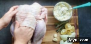 A hand gently separates the turkey's breast skin from the meat, creating a pocket for the herb butter without puncturing the skin.