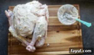 The turkey cavity is stuffed with lemons, onions, garlic, and fresh herbs, and the legs are tied together with cooking twine.