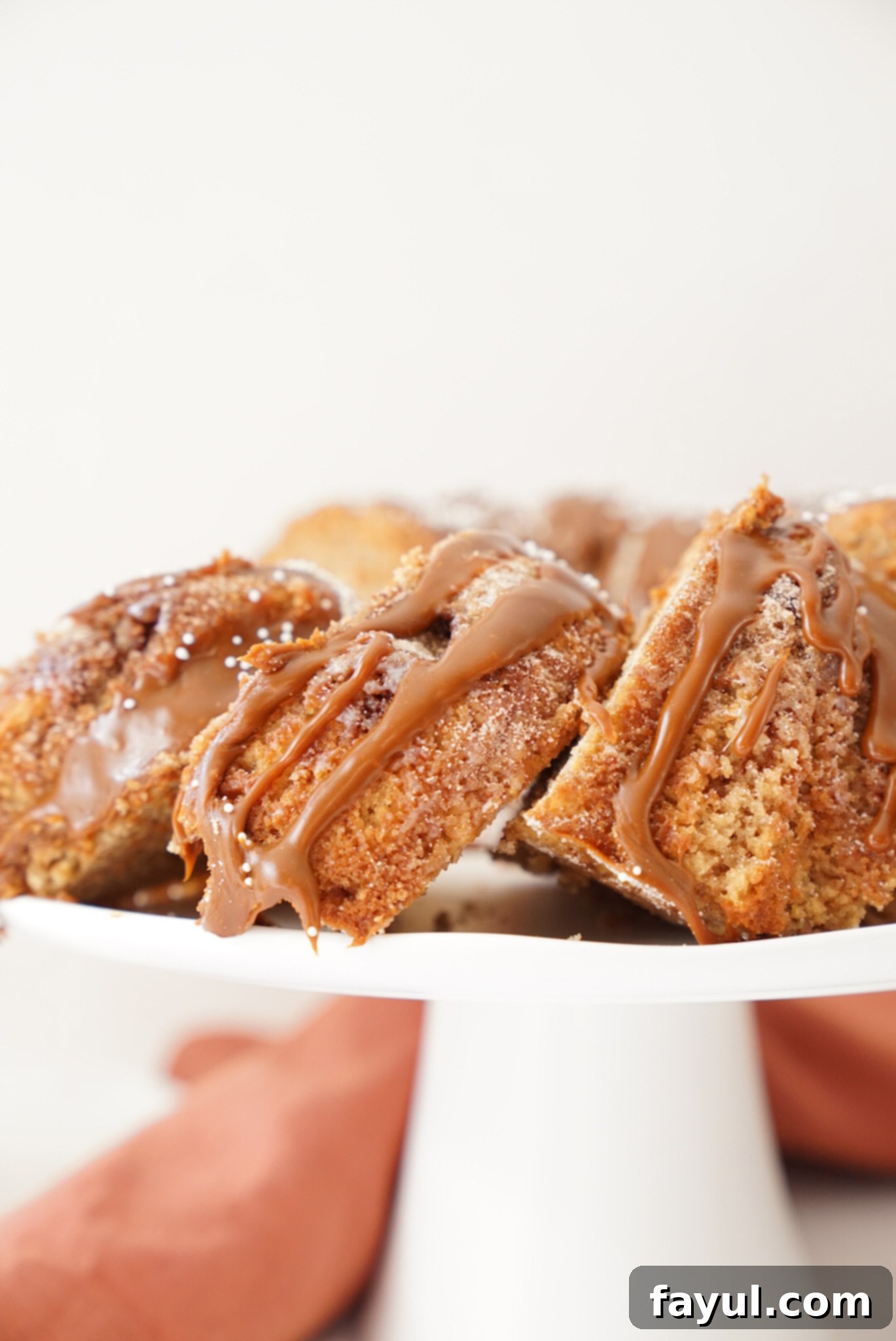 A delicious slice of churro bundt cake on a white plate, showing the moist crumb and cinnamon sugar swirl, with ganache drizzle.