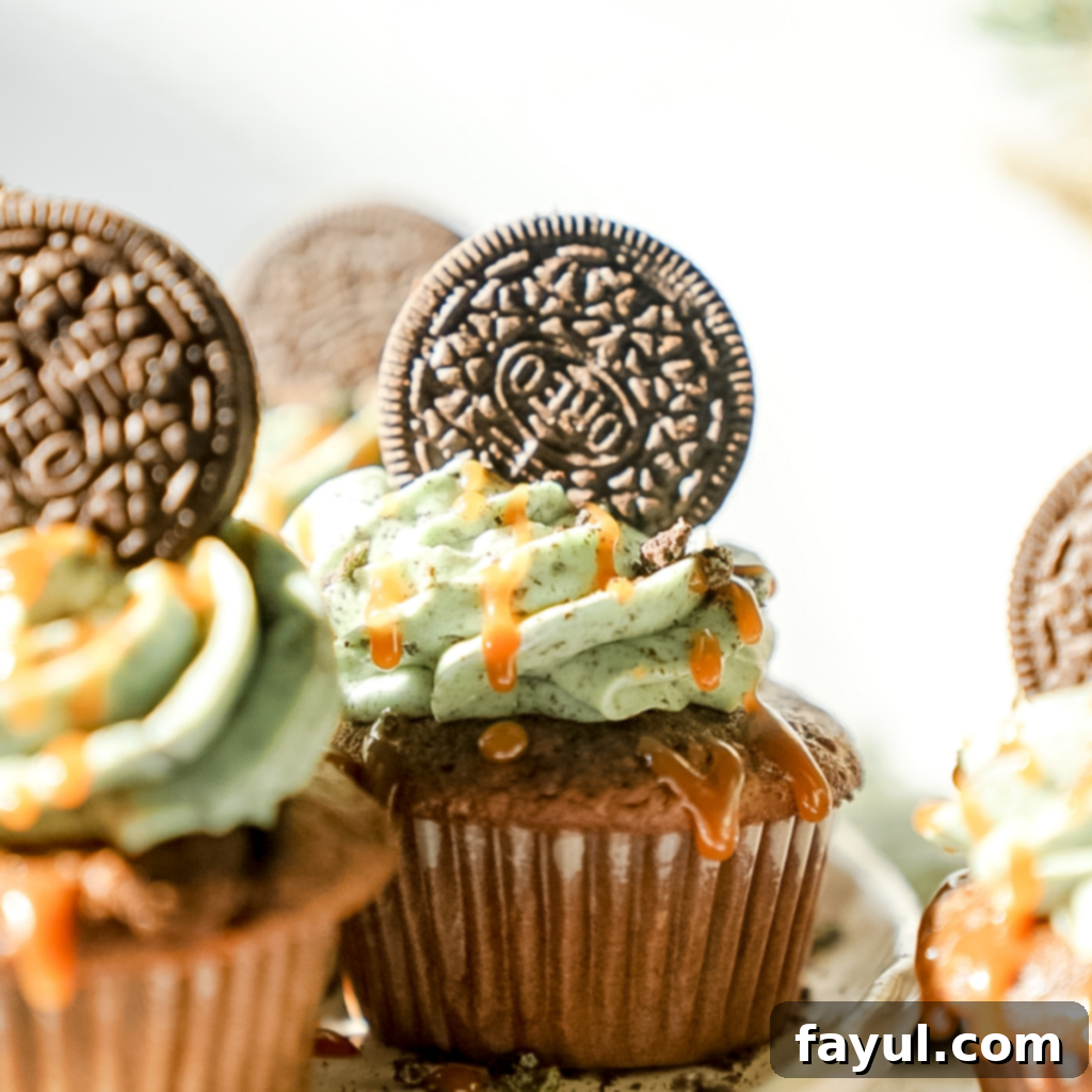 An overhead shot of several Grasshopper Caramel Cupcakes, showcasing their vibrant green mint Oreo frosting, whole Oreo toppings, and generous caramel drizzles.