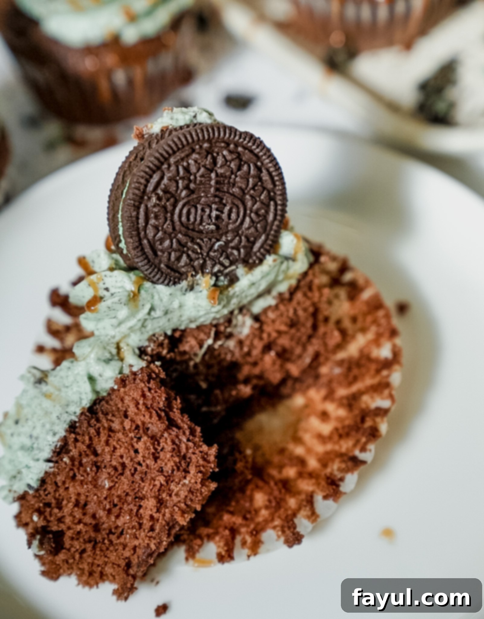 A close-up of a bowl filled with fluffy, pale green mint Oreo buttercream, showing the crushed Oreo pieces mixed in.