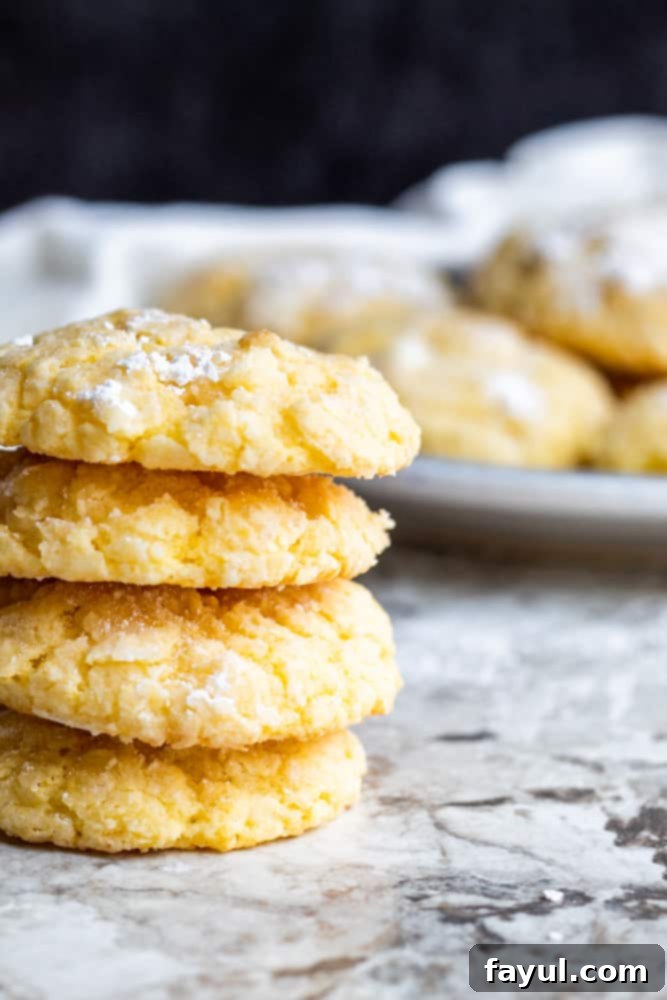 A beautifully arranged stack of three Gooey Butter Cake Cookies, with a subtle blur of a plate in the background, highlighting the cookies as the main focus.