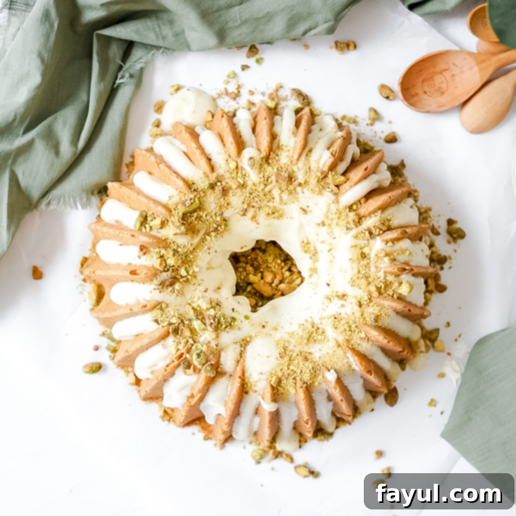 A beautifully decorated lemon pistachio bundt cake with a smooth lemon cream cheese glaze and sprinkled crushed pistachios.