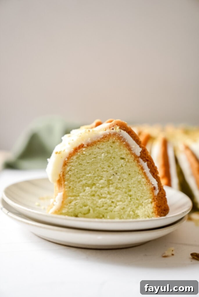 A freshly baked lemon pistachio bundt cake, perfectly golden brown and still in the bundt pan, cooling on a wire rack.