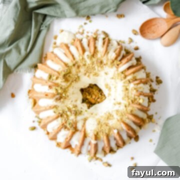 A beautiful, single slice of pistachio lemon bundt cake on a white plate, drizzled with lemon cream cheese glaze and garnished with crushed pistachios.