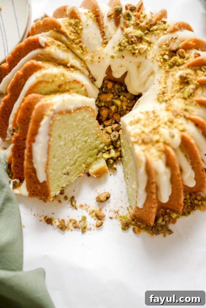 A close-up shot of the top of the lemon pistachio bundt cake, showcasing the textured surface and the glossy lemon cream cheese glaze.