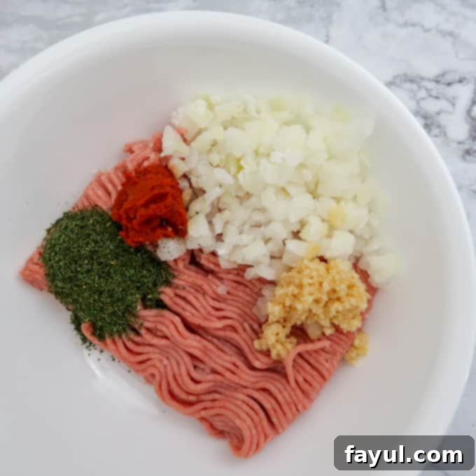 Overhead view of burger patty ingredients in a white bowl, perfectly mixed and ready to be formed.