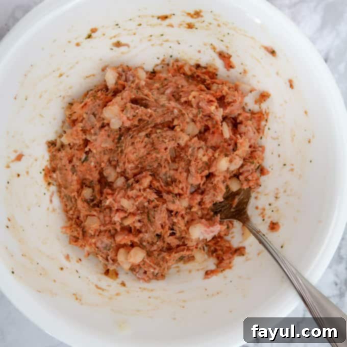 Overhead view of ground turkey mixed with onion, garlic, red curry paste, and dried cilantro.