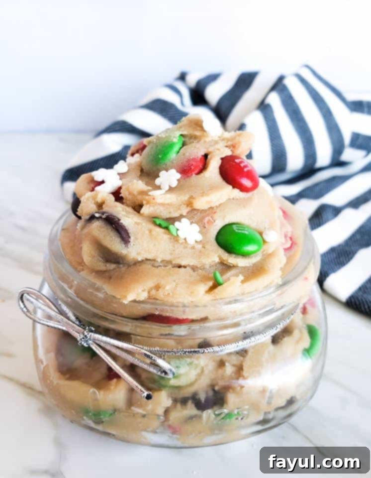 Glass mason jar with cookie dough in it on white counter, perfect for a gift.