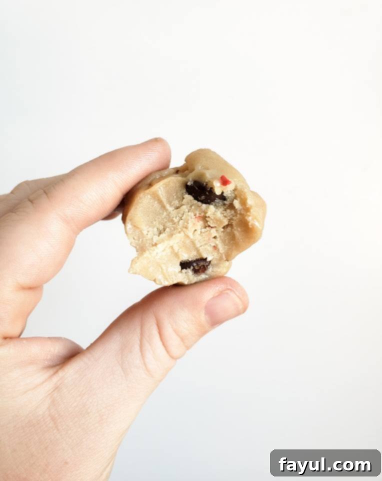 Hand holding a ball of edible cookie dough, ready to be eaten.