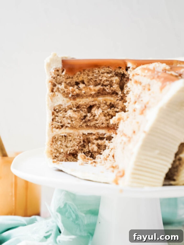 Slice of Gooey Cinnamon Roll Caramel Cake with visible layers, buttercream, and caramel drizzle
