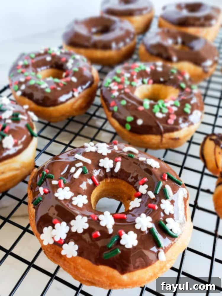 An inviting angled shot of several perfectly glazed chocolate donuts, topped with colorful sprinkles, ready to be enjoyed.