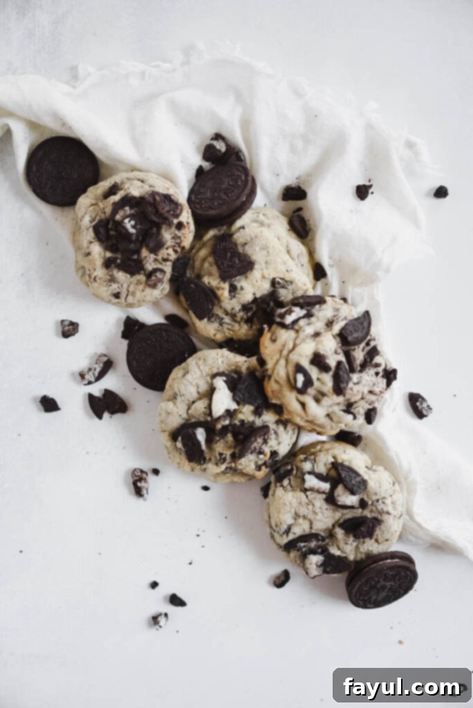 Assortment of fresh baking ingredients including cold butter, eggs, flours, sugars, Oreos, and dark chocolate chips, ready for making cookies.