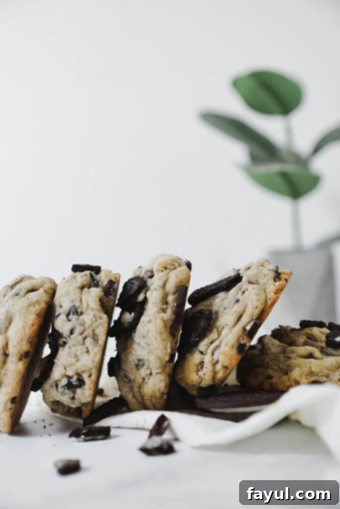 Raw cookie dough balls, generously garnished with crushed Oreo chunks, arranged on a baking sheet lined with parchment paper, ready for baking.