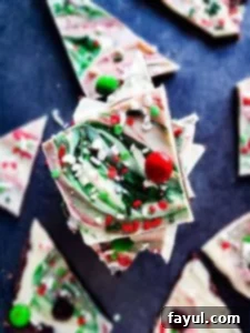 Christmas chocolate bark stacked on top of each other on a blue counter top, showcasing two chocolate layers with festive toppings.